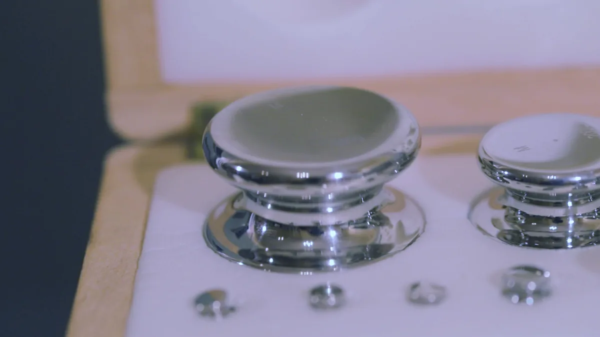 Polished stainless calibration test weights in a fitted wooden case, including small fractional weights.